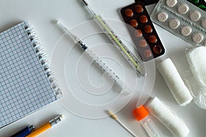 Medical thermometer and pills for the treatment of disease on a white background.