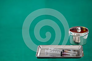 Medical tools jar tray syringe on green background with copy tex