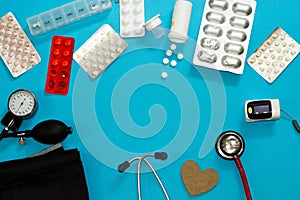 Medical tools and pills blisters for theat and diagnose patients on blue background with copy space. Stethoscope, cuff, pulse photo