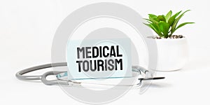 MEDICAL TOURISM word on notebook,stethoscope and green plant