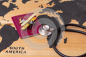 Medical travel concept. stethoscope passport document and toy airplane on wooden world map background