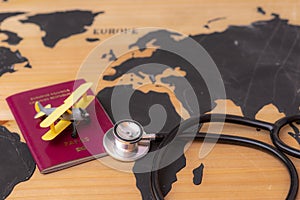 Medical travel concept. stethoscope passport document and toy airplane on wooden world map background