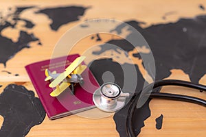 Medical travel concept. stethoscope passport document and toy airplane on wooden world map background