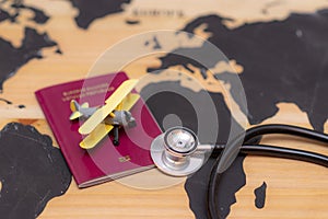 Medical travel concept. stethoscope passport document and toy airplane on wooden world map background
