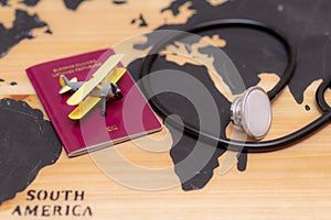 Medical travel concept. stethoscope passport document and toy airplane on wooden world map background