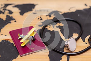 Medical travel concept. stethoscope passport document and toy airplane on wooden world map background