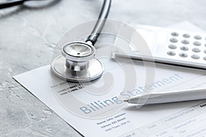 Medical treatmant billing statement with stethoscope and calculator on stone background