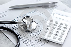 Medical treatmant billing statement with stethoscope and calculator on stone background