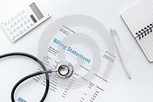 Medical treatmant billing statement with stethoscope and calculator on white background top view mock up