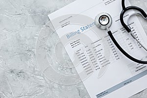 Medical treatmant billing statement with stethoscope on stone background top view mockup