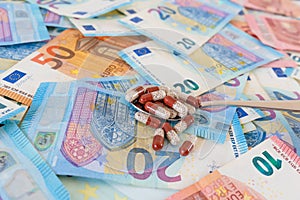 Medical treatment, healthcare high costs concept, spoon with pills on euro banknotes