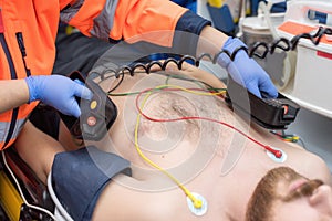 Medical urgency in the ambulance. Emergency doctor using defibrillator