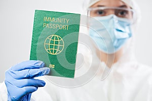 Medical US healthcare security officer worker in personal protective equipment holding green immunity passport ID card