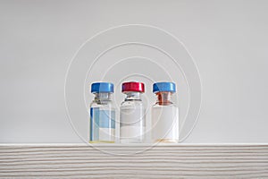 medical vaccine vials or bottles on table top over gray background. blank vial template for label. empty white label on the bottle