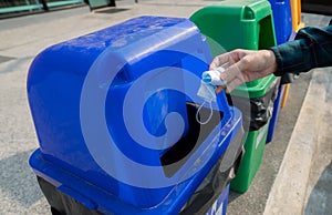 Medical waste. People hand throwing used medical protective face mask in recycle bin. Blue plastic recycle bin. Man discard used