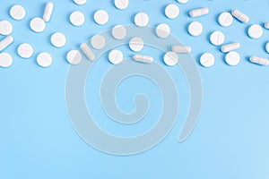 Medical white pills and pills on a blue background. The concept of healthcare, medical care