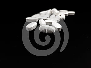 medical white tablets or pill on black background , isolated closeup