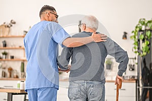 Medical worker assisting his patient to walk with a cane