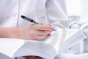 Medical worker, doctor or nurse holding a large reference book with a ballpoint pen