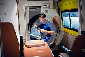 Medical worker on duty, surching for something in his medical kit in an ambulance