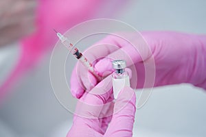 Medical worker holding an injection syringe and small glass vial