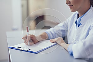 Medical worker is jotting down in clipboard