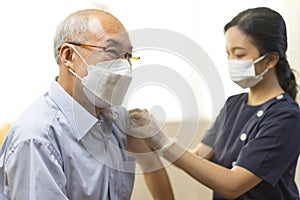 Medical worker or nurse perform a vaccine injection to senior Asian man in clinic