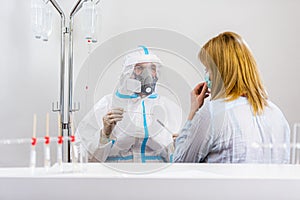 Medical worker in PPE performing nasal swab COVID-19 test in hospital lab