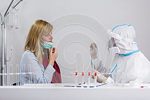 Medical worker in PPE performing nasal swab COVID-19 test in hospital lab