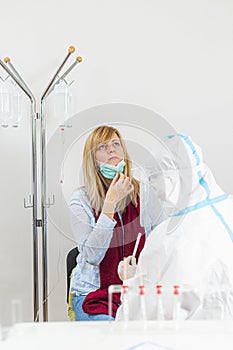 Medical worker in PPE performing nasal swab COVID-19 test in hospital lab