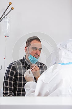 Medical worker in PPE performing nasal swab COVID-19 test in hospital lab