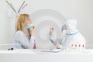 Medical worker in PPE performing nasal swab COVID-19 test in hospital lab