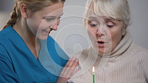 Medical worker presenting elderly lady birthday cake, taking care and support