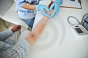 Medical worker pressing her fingers to a wrist vein