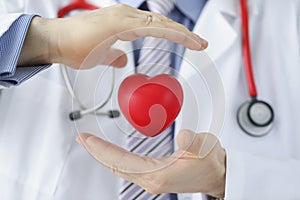 Medical worker protect plastic red heart, doctor cover heart model with hands