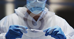 Medical worker in protective clothing and face mask examining patient swab test