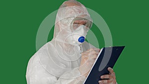 Medical worker in protective costume and mask writing on clipboard. Bio engineer in safety suit writing in clip board on