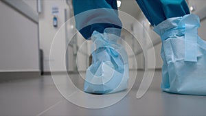 Medical worker in protective suit with overshoes in hallway