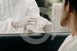 Medical worker in protective suit screening woman Driver to Sampling secretion to check for Covid-19