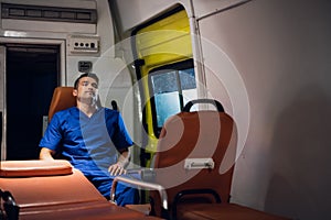 Medical worker sitting in an ambulance car, having a rest, meditating