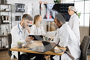 Medical workers with gadgets having meeting at clinic