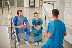 Medical workers sitting on the stairs and having coffee break