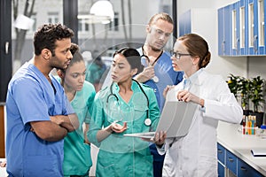 Medical workers using laptop during discussion in lab