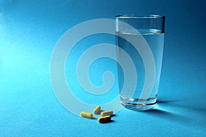 Medical yellow capsules medication with a glass of water