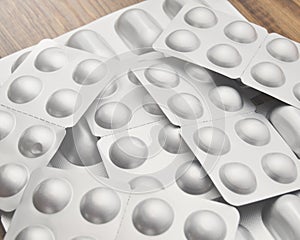 Medicaments on a wooden table. Many tablets in silvery blisters