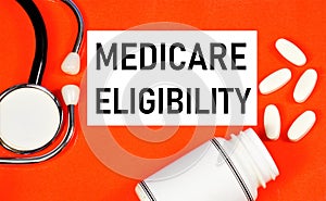 Medicare eligibility. Text label in the folder on the background of medicines. photo
