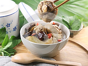 Medicated sesame chicken in white bowl on wooden table with herb photo