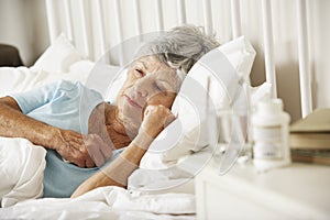 Medication On Bedside Table Of Sleepless Senior Woman