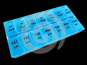 Daily medication drug dispenser pills vitamins blue pill box isolated on black background days of week