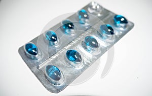 Medication in the form of a pack of blue pills on a gray background